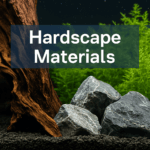 A digital photograph with overlaid text showcases a freshwater aquascape with Seiryu stone and driftwood placed over dark aquarium soil, set against a background of lush green aquatic plants, labeled 'Hardscape Materials'